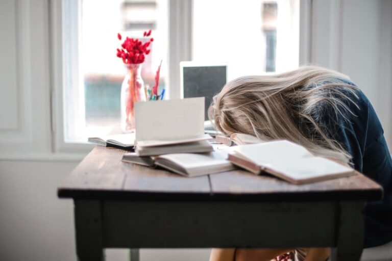 Una mujer agobiada por su trabajo descansa brevemente sobre su escritorio.